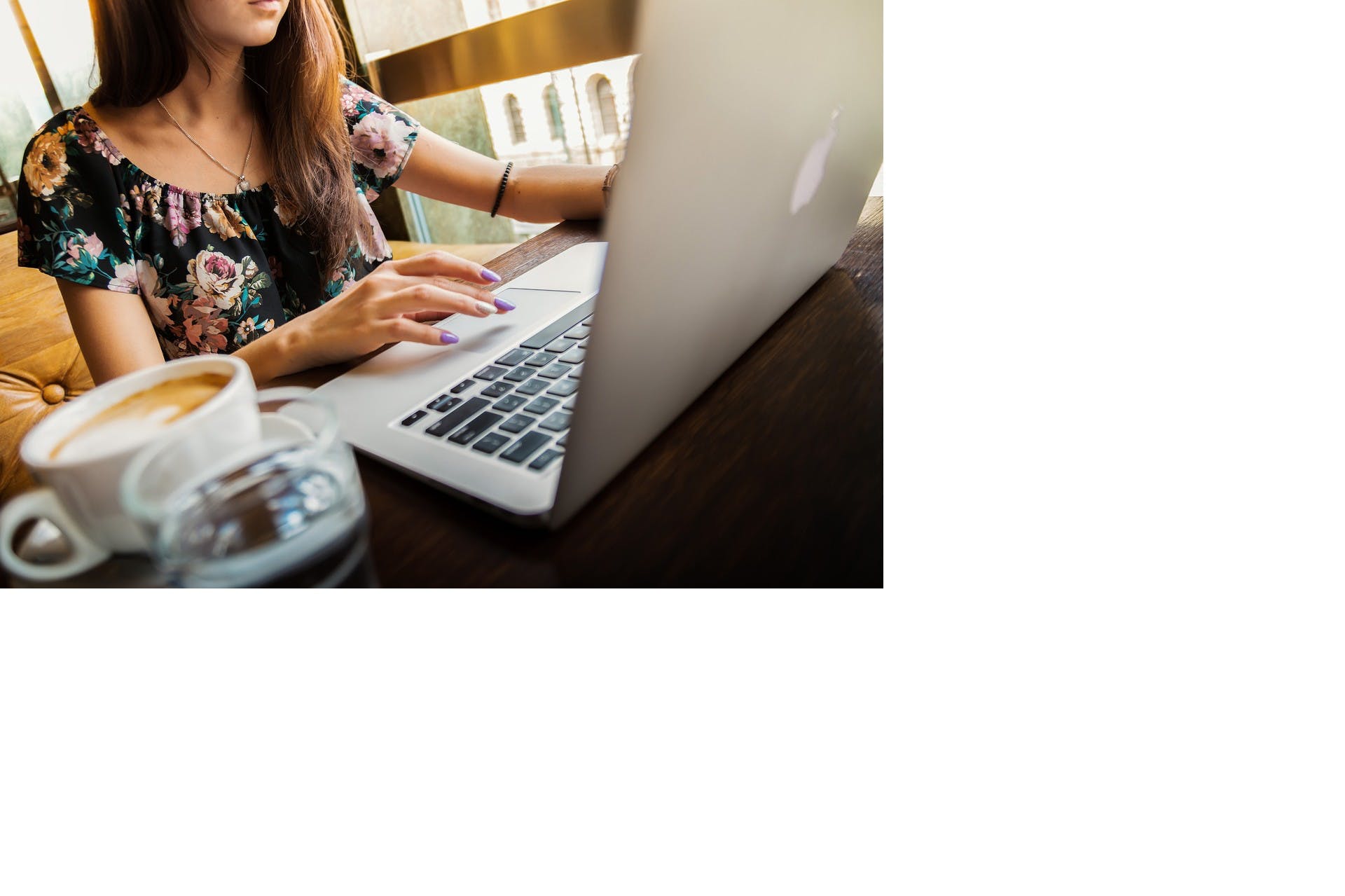 Girl sitting and working on her macbook with a cup of coffee