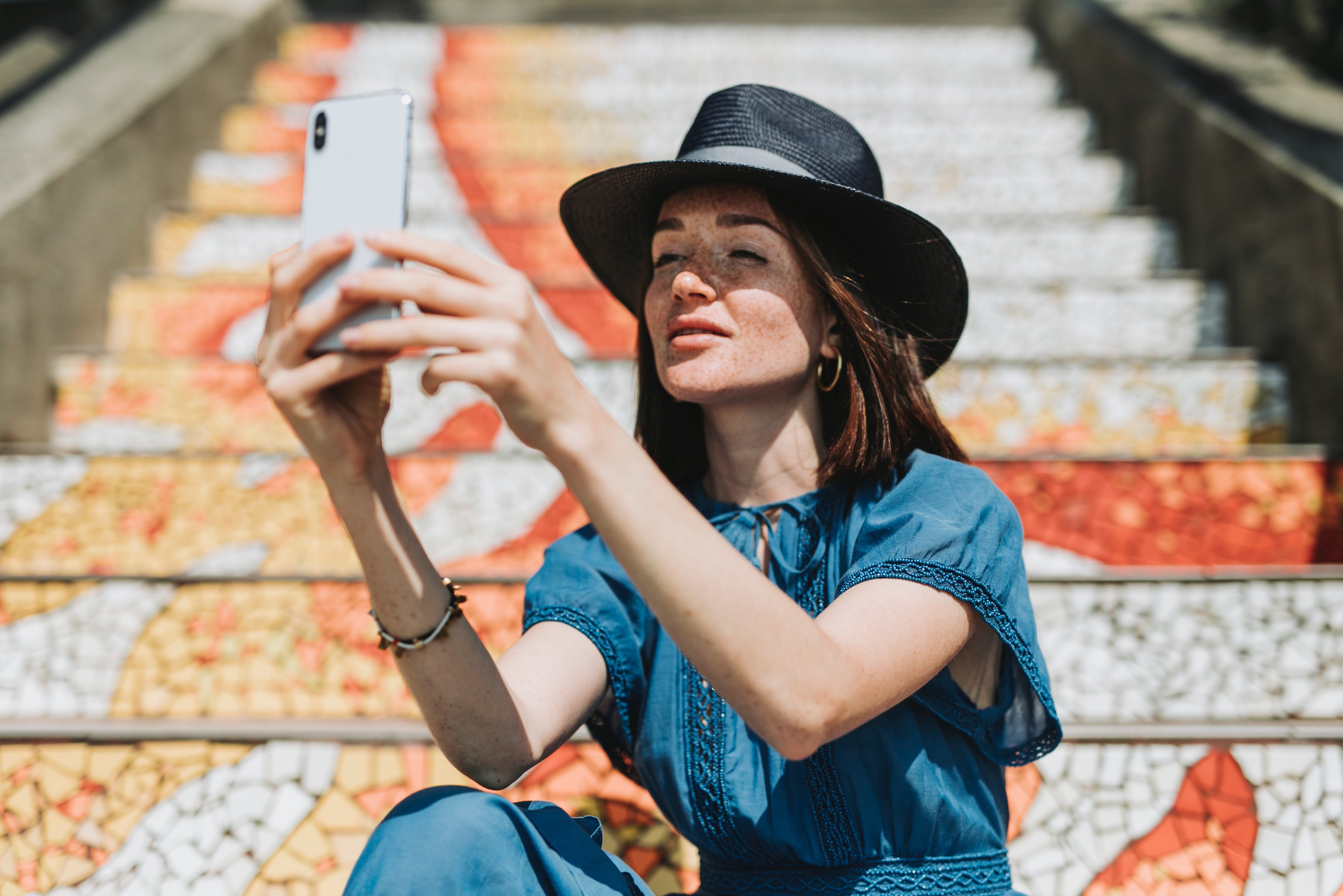 A girl sitting on a staircase and taking a selfie