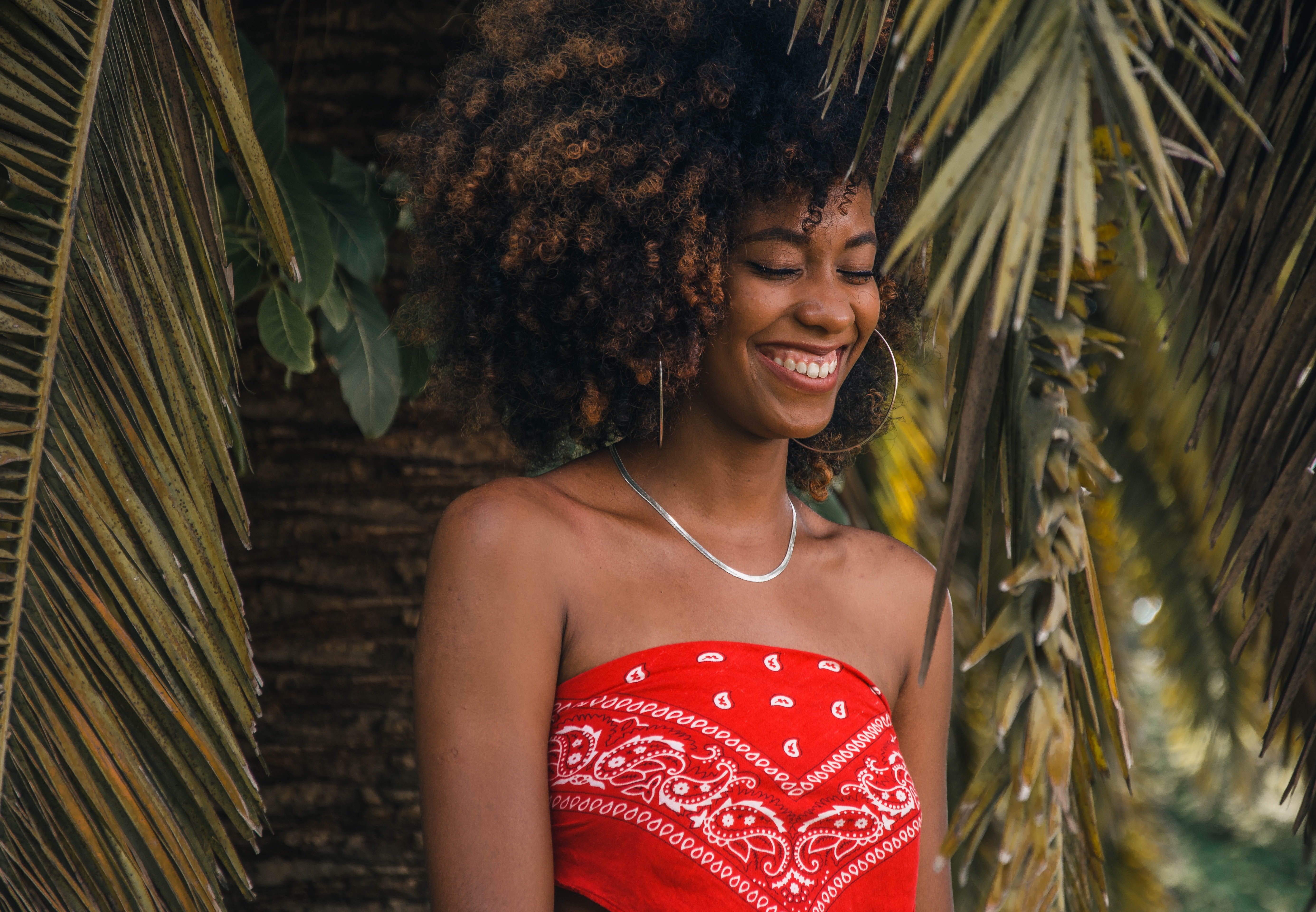 Girl smiling and summer dressed posing in front of a palm tree