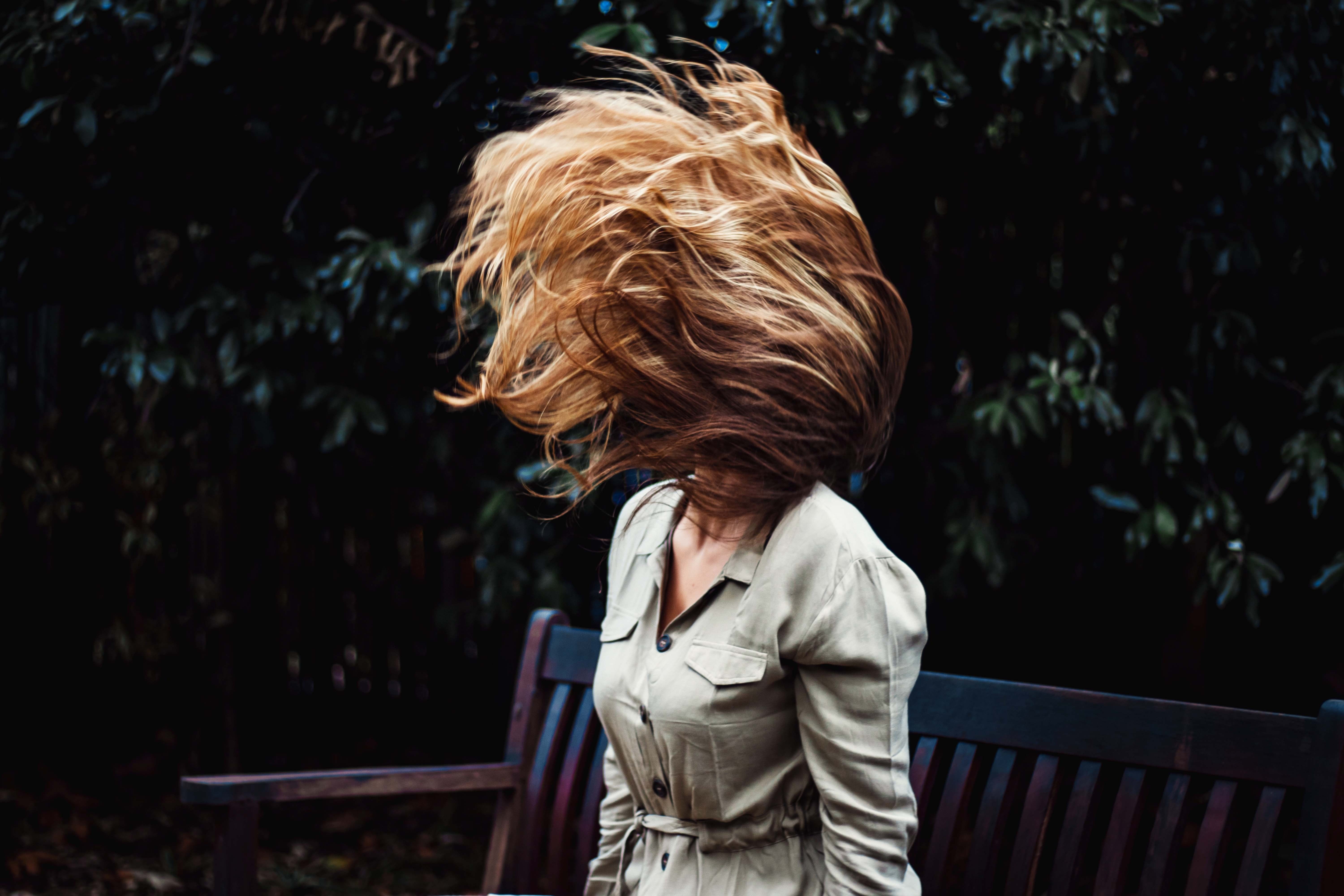 Girl waving her hair in the air with green plants in the background