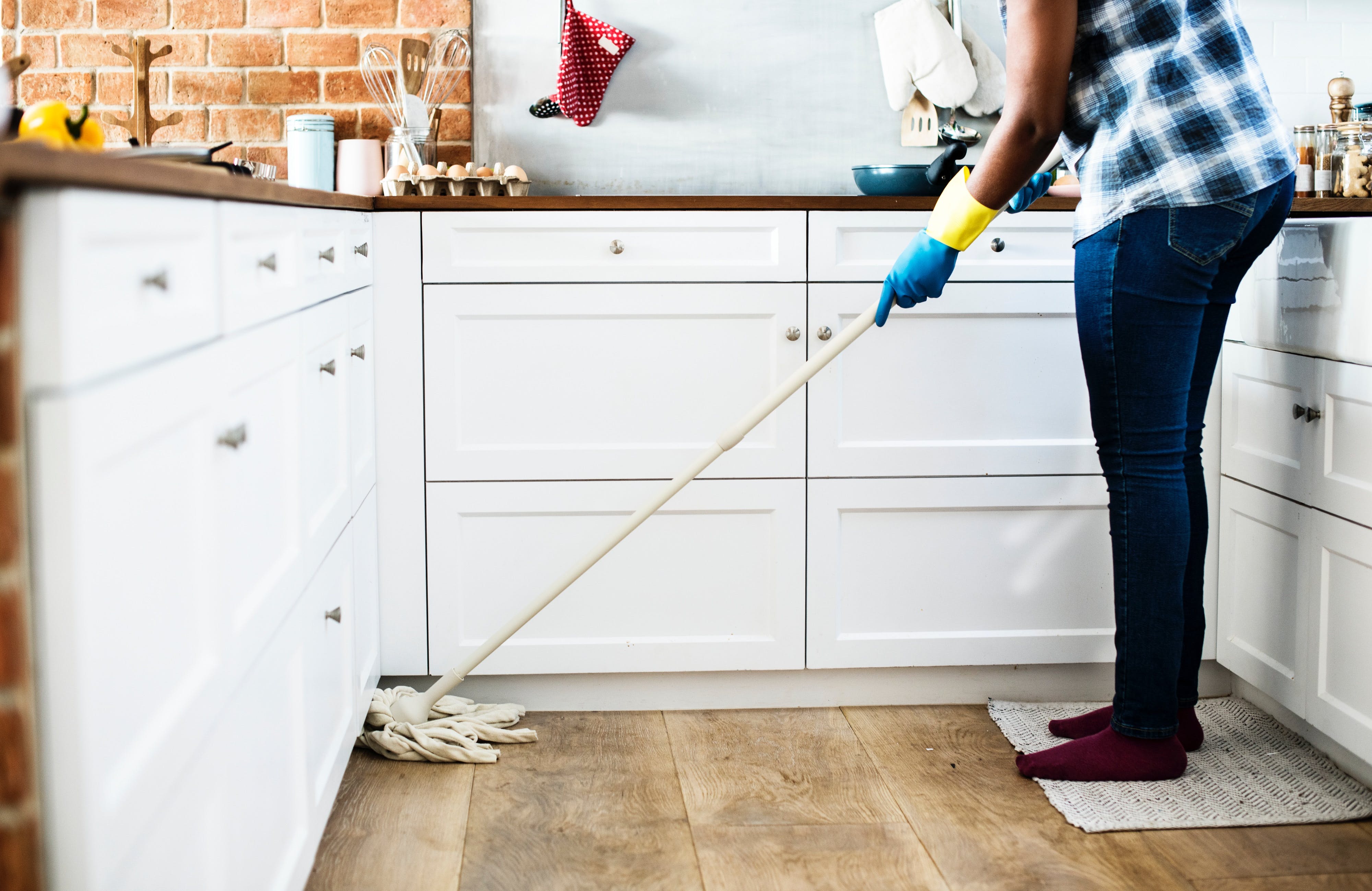 Person holding a mop and cleaning in a white kitchen