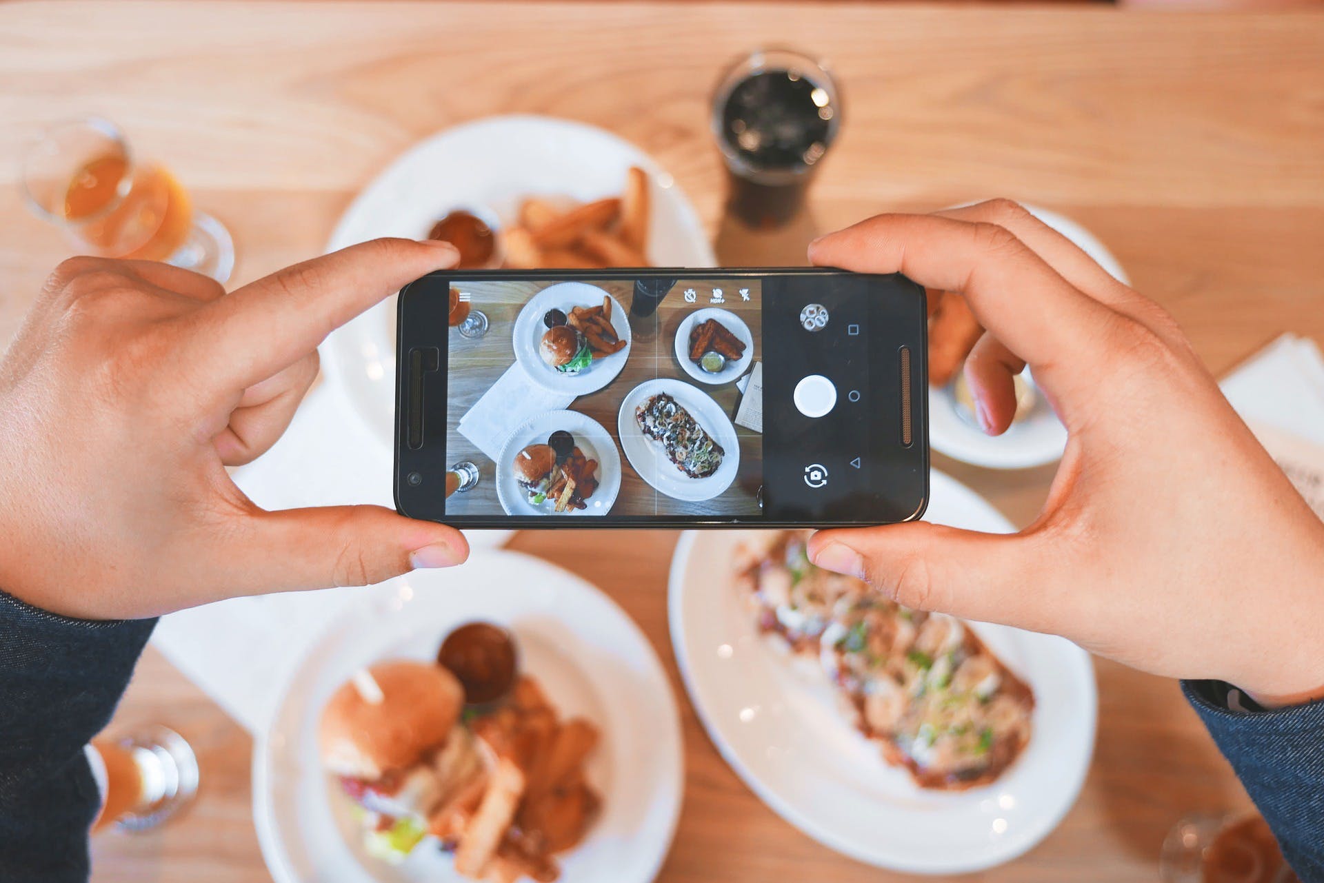 Person holding a phone and taking a picture of their food