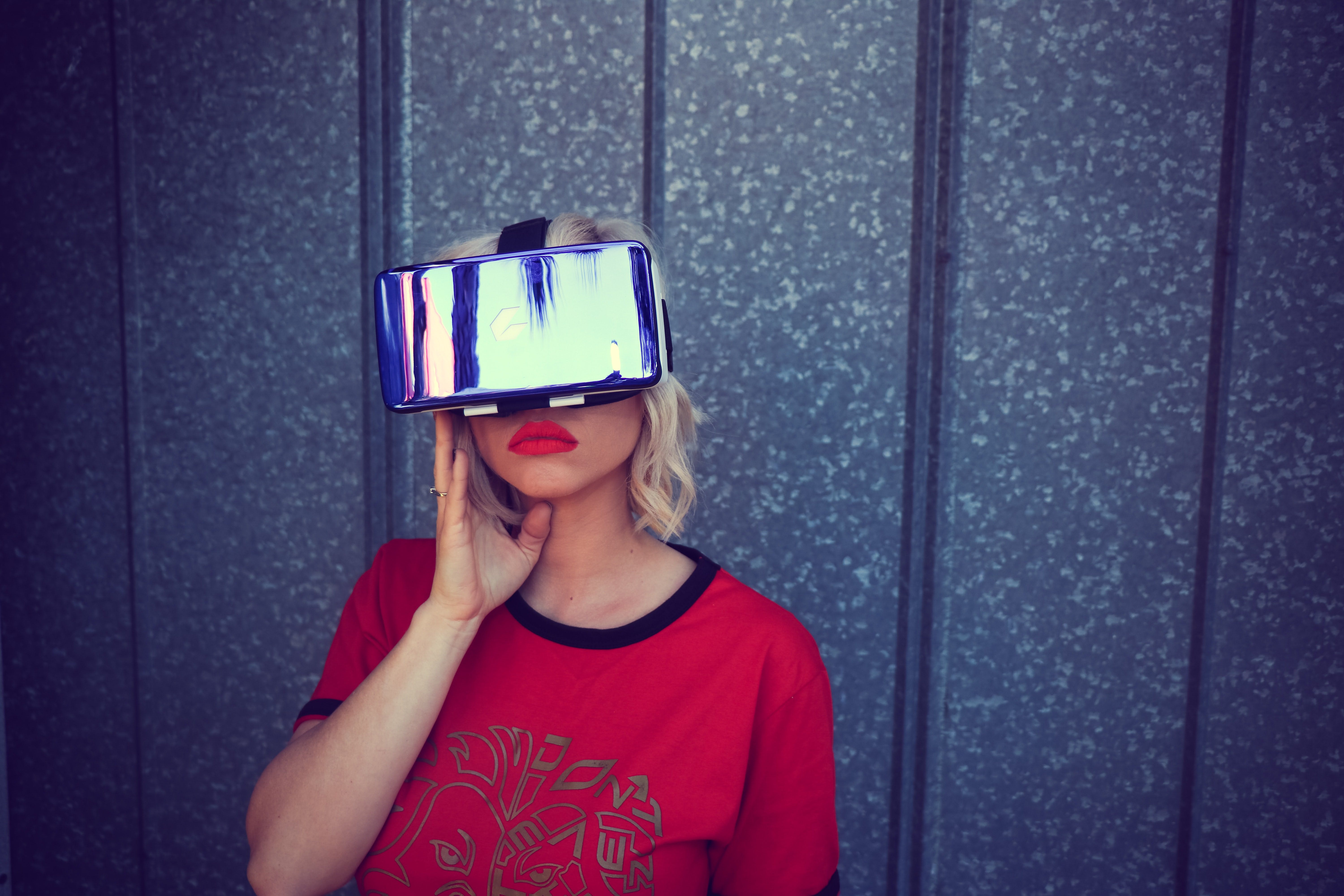 A girl with red sweater and lipstick are wearing a VR-headset and posing