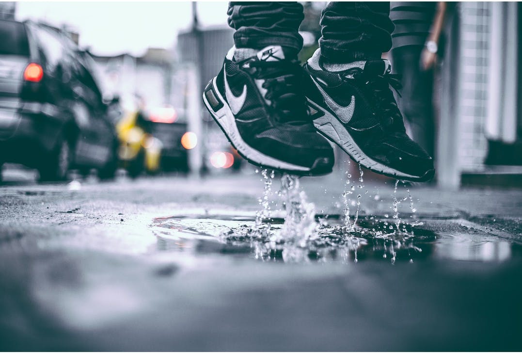 Person wearing Nike Sneakers and jumping from a puddle