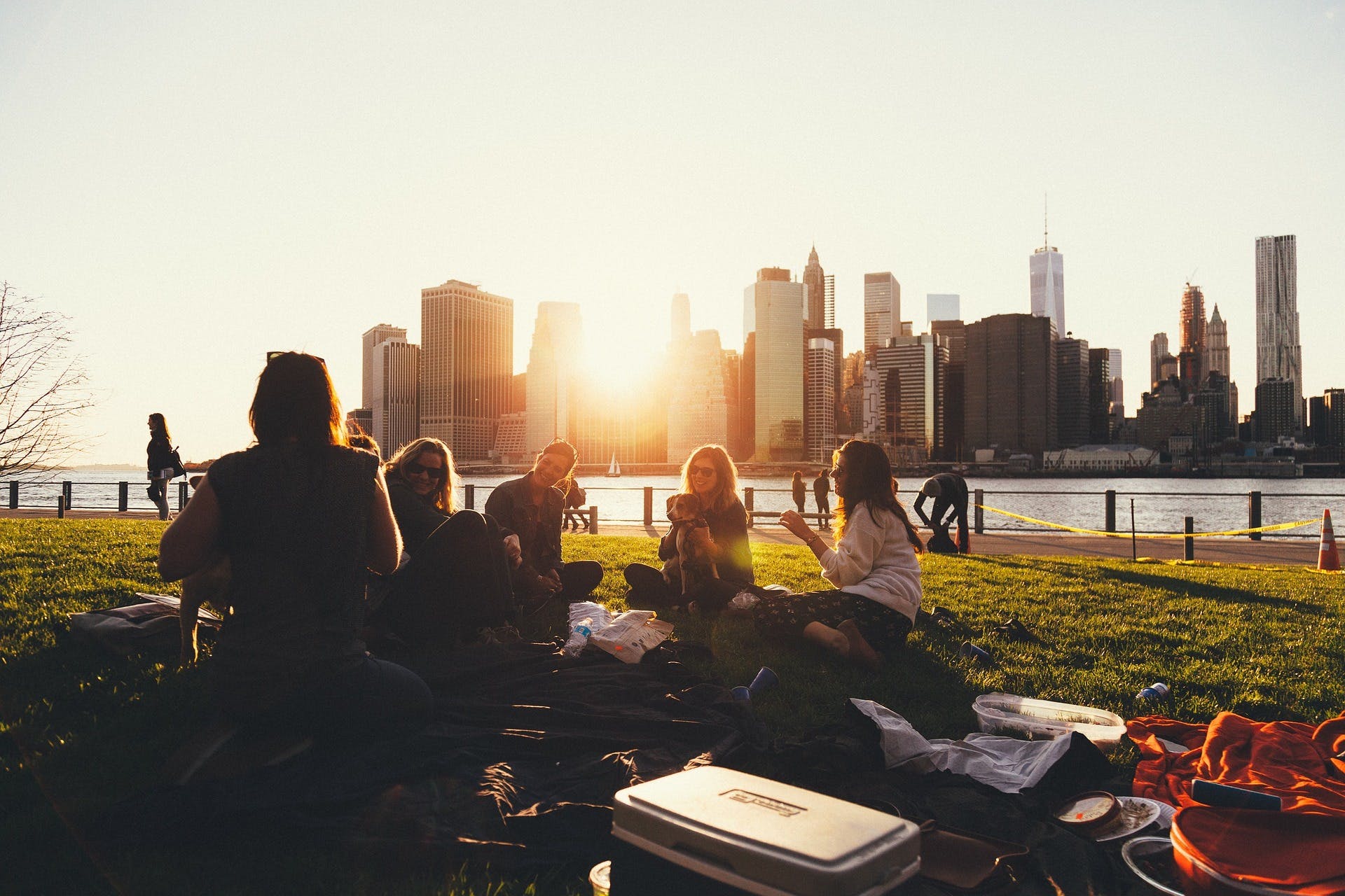 A group of people sitting down in the park at sunset in New York 
