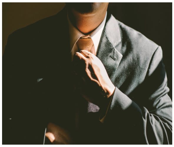 Man in a suite corrects his tie