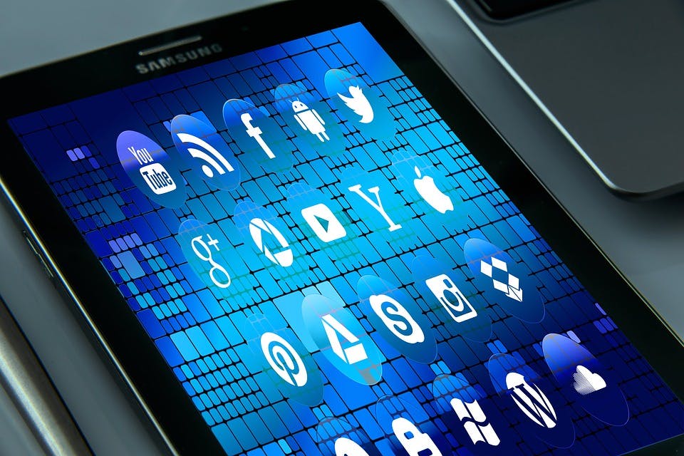 En tablet med blå bakgrund som visar en massa sociala medier ikoner och andra appar